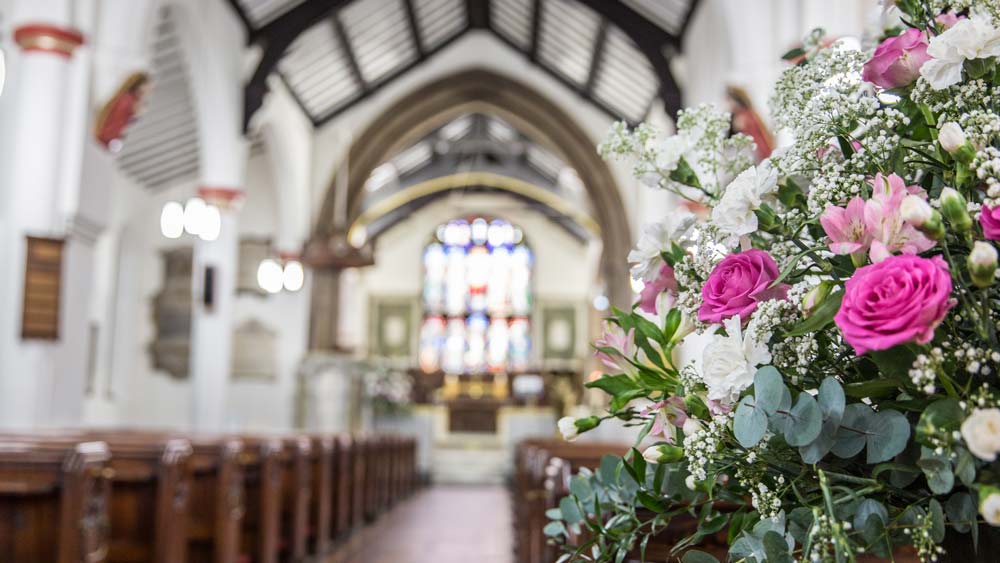 A view of the chancel from the aisle at St James, with a display of white and pink carnations in the foreground.