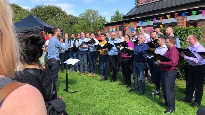 A choit of gay men sing a capella in the grounds of Emmanuel church at the first Didsbury Pride