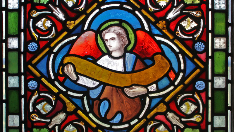 Stained glass window detail depicting an angel holding a scroll