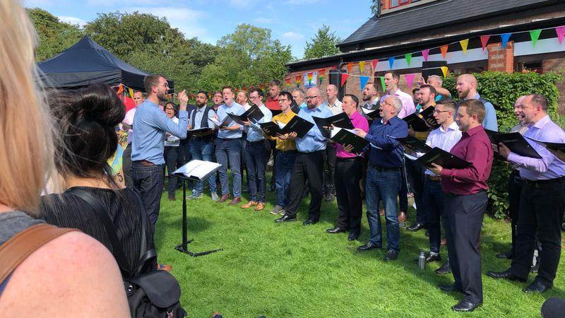 A choir of gay men sing a capella in the grounds of Emmanuel church at the first Didsbury Pride