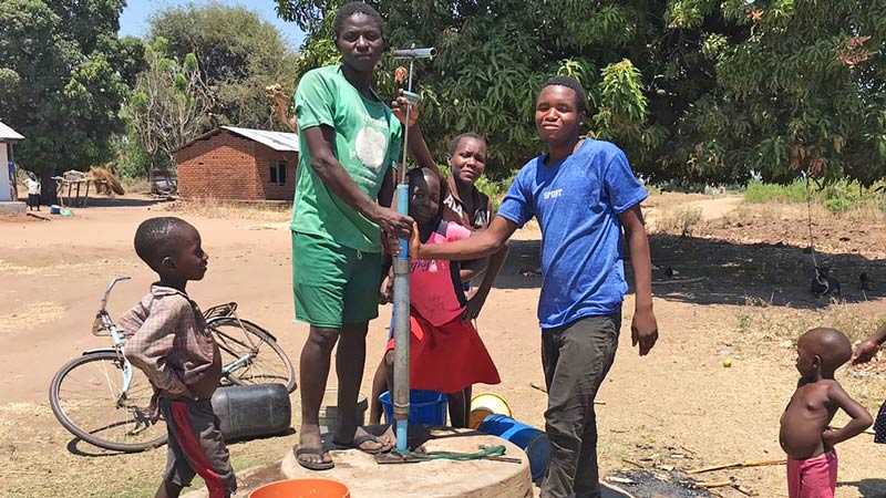 Malawi villager Joseph Magwa stands proudly by a new water pump.
