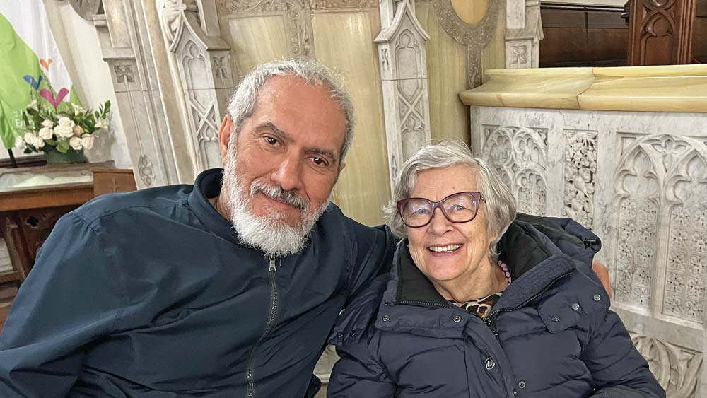 A smiling Maggie and Pascal, both wheelchair users, in St James