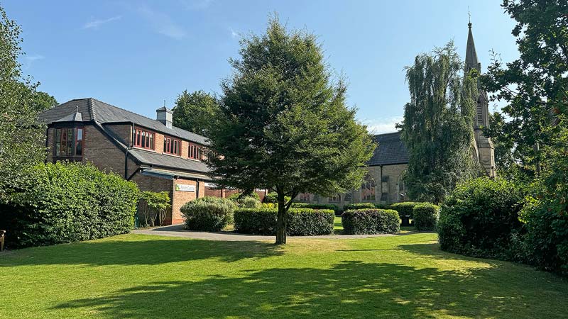 The verdant tree-lined grounds behind Emmanuel church and in front of the Parish Centre