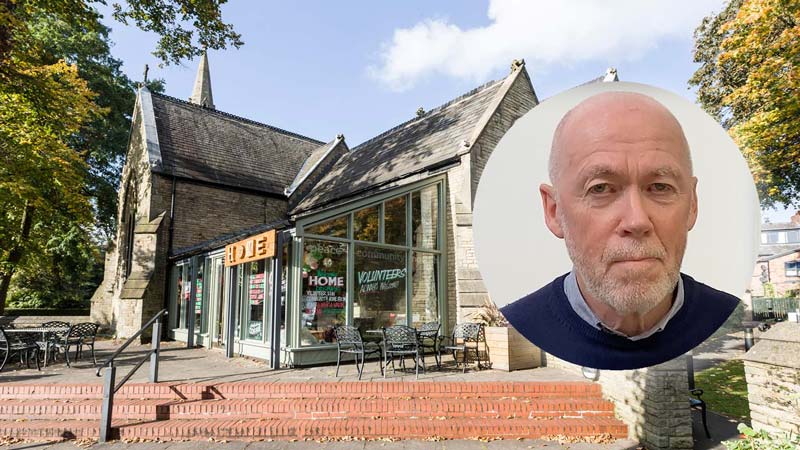 A view of the entrance to Emmanuel, a stone church building with a modern glass extension. There are outdoor tables and chairs on a brick patio surrounded by trees. A circular inset photo shows a smiling Chick Yuill. He is wearing a dark blue sweater over a light blue shirt.