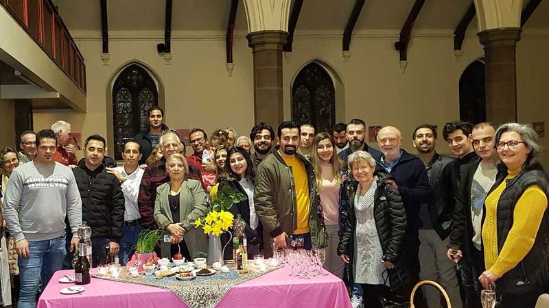 A group of the Taban Farsi community gather in a Manchester church to enjoy a food and drink.