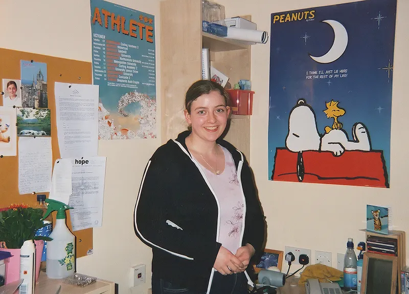 Rosalind in her room standing next to a large poster featuring Snoppy from the Peanuts cartoon